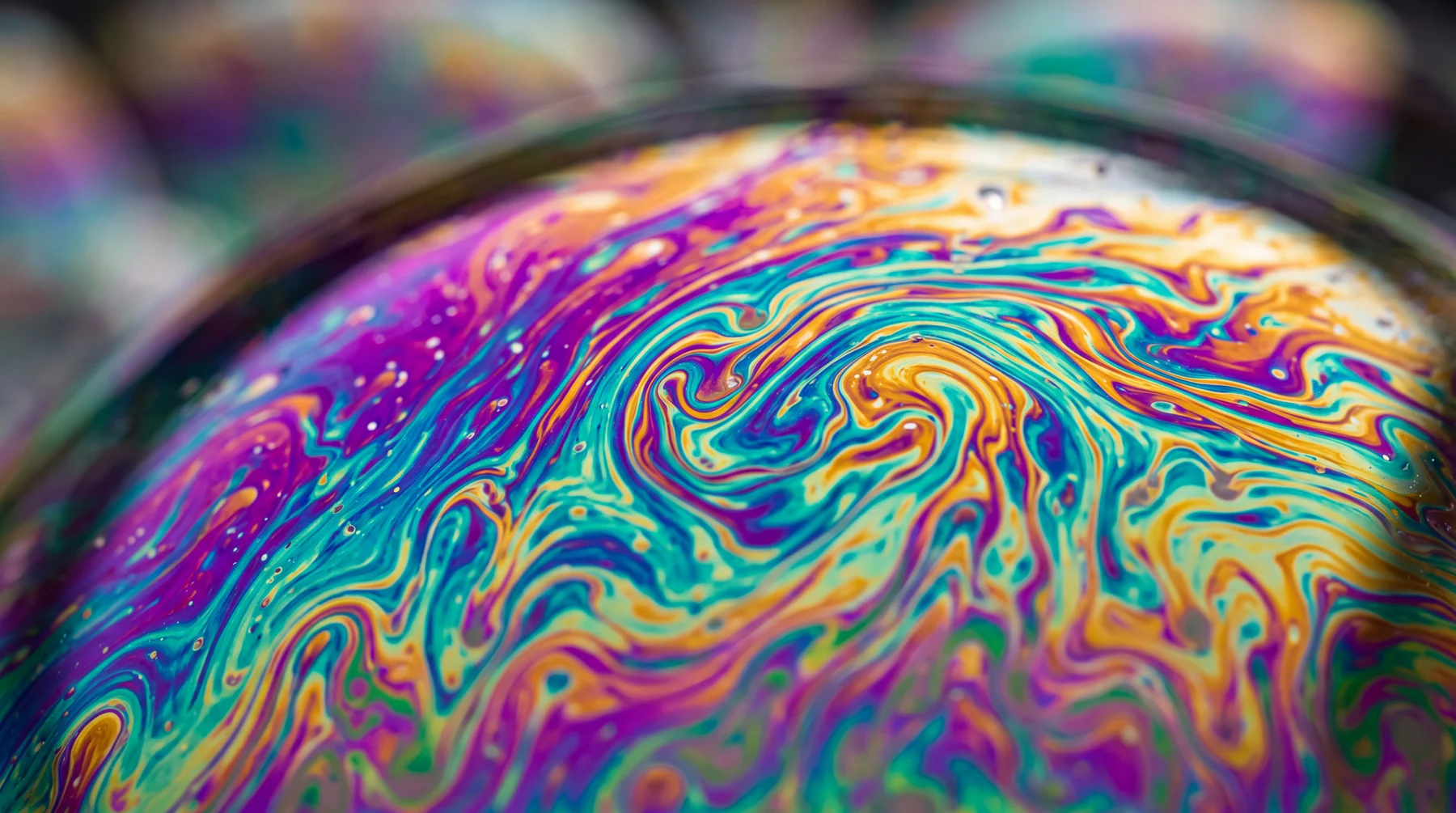 Macro de película de jabón con colores iridiscentes violeta, turquesa y oro